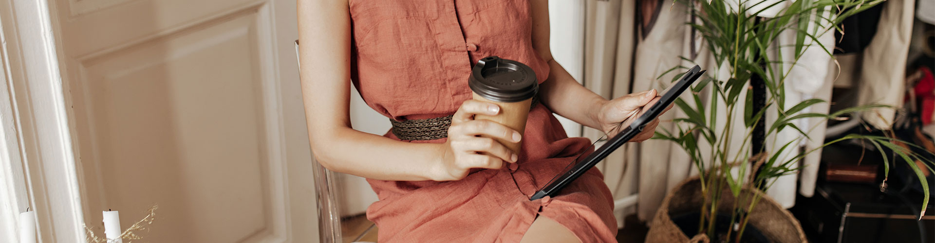 mulher sentada com copo de café na mão e na outra um tablet, exemplo de consumidor do futuro